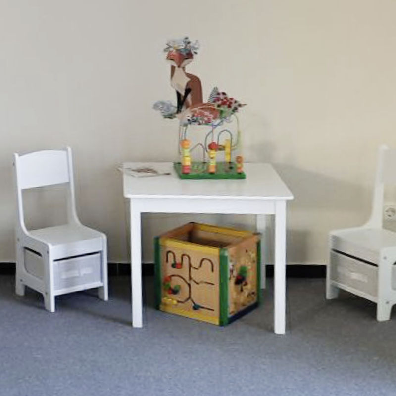Ein heller Raum mit einem Tisch, zwei Stühlen und buntem Spielzeug.